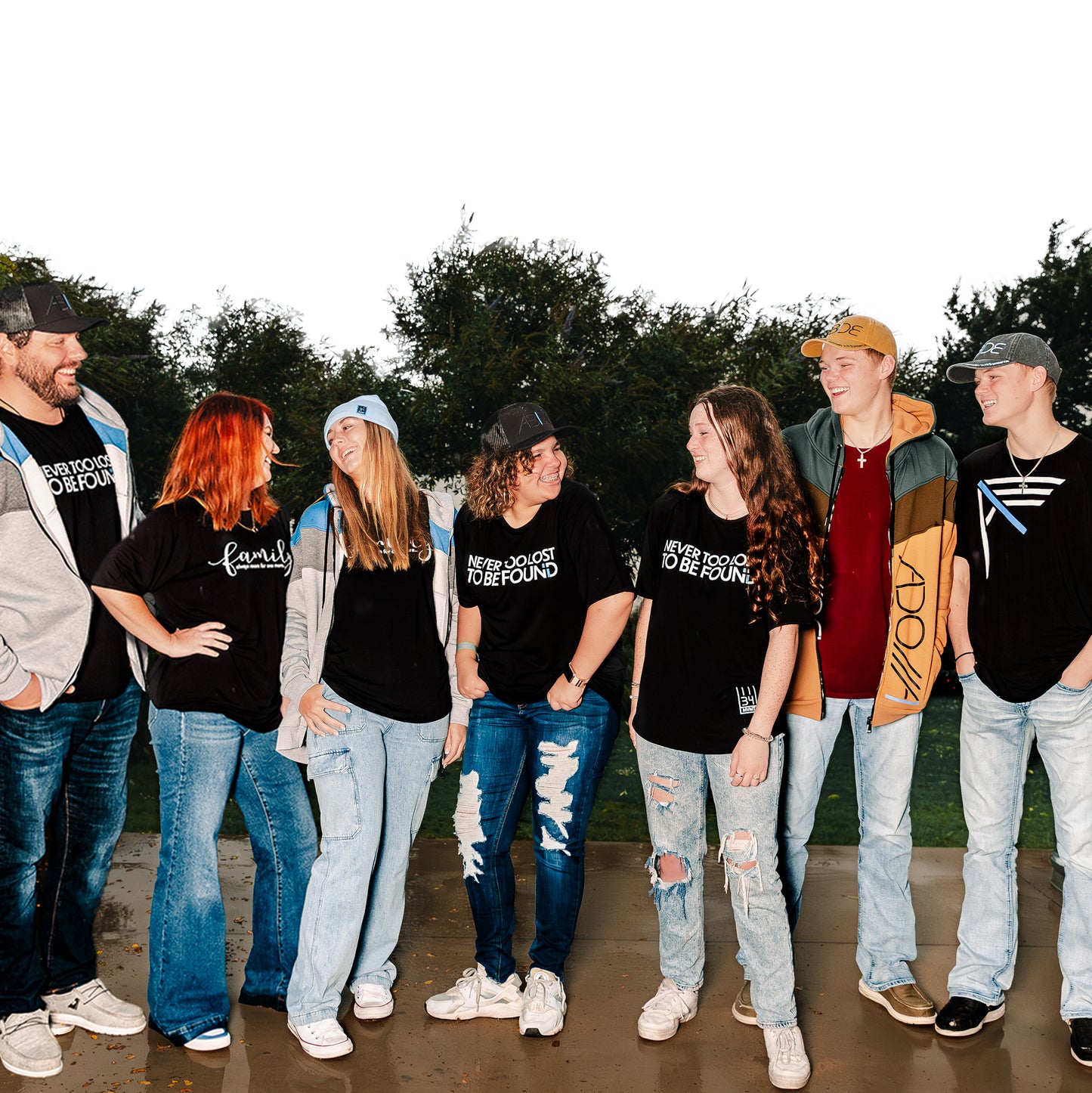 Christian Family and friends gathering, laughing wearing Now Found Chrisitan Apparel Never Too Lost Bamboo Tees, I AM Royal zip-up hoodies ABIDE trucker and dad hats and family bamboo tees
