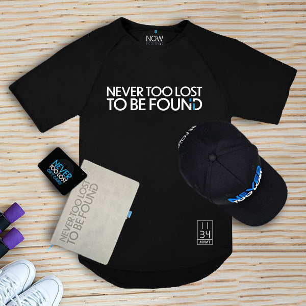 The Cultivation Bundle Collection of 'Never Too Lost' branded merchandise including a shirt, hat, journal, and more on a bamboo background.