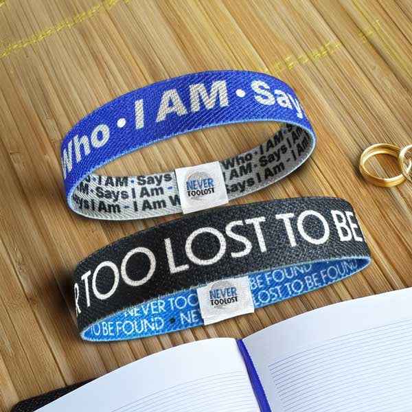 Never Too Lost and I Am Who I AM Says I Am Wristbands on bamboo next to journal