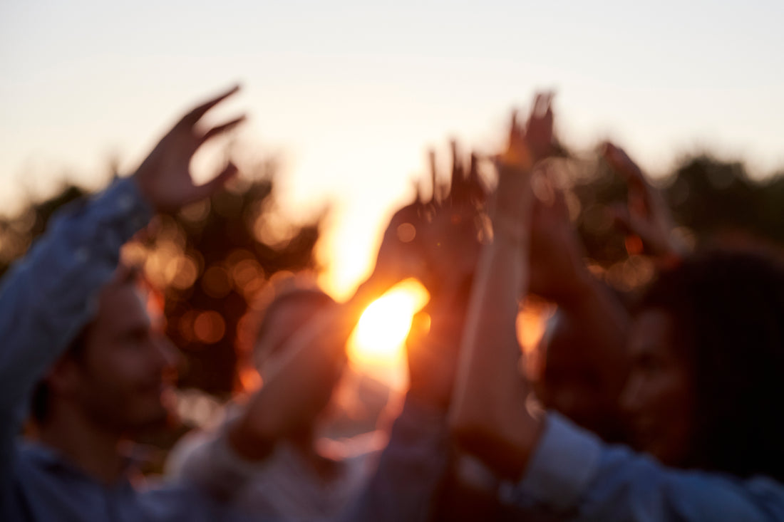 Portrait of four young adults with arms raised By monkeybusiness