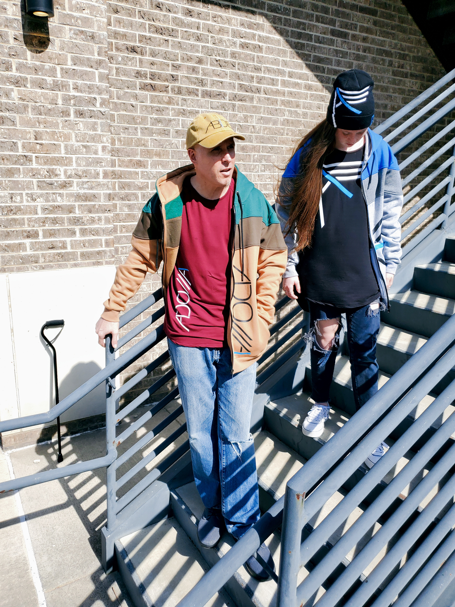 Two models on steps wearing Now Found Apparel's Blue Letter Collection including the ABIDE, I IAM, and ADONAI lines of clothing.