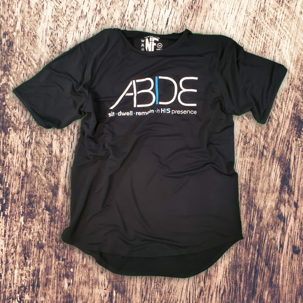 Black Christian Apparel with 'ABIDE' sit - dwell - remain in His Presence on a wooden surface