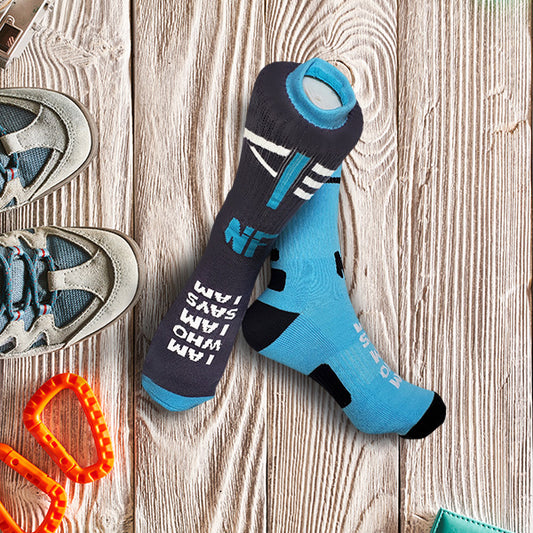 Blue and Gray I Am Who I AM Says I Am socks on a wooden surface with shoes and carabiner.
