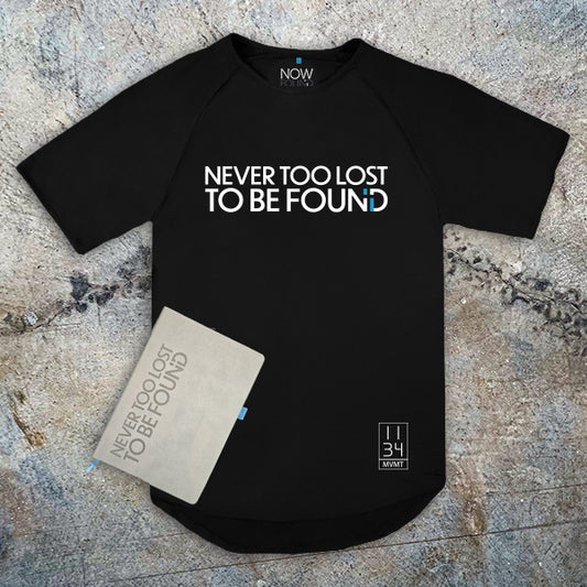 Black t-shirt and Christian Journal with 'Never Too Lost To Be Found' text on a textured surface