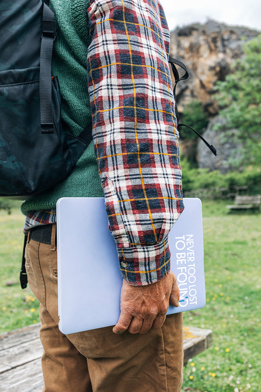 man hiking carrying laptop with Never Too Lost To Be Found sticker on it.