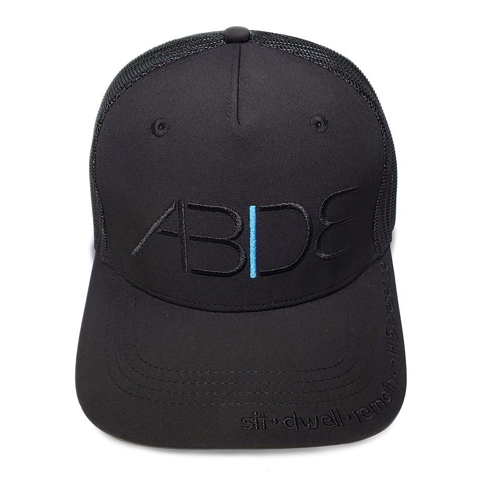 black abide blackout trucker hat front view with sit dwell remain in his presence on bill